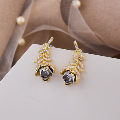Elegant gold leaf earrings with a silver rose accent